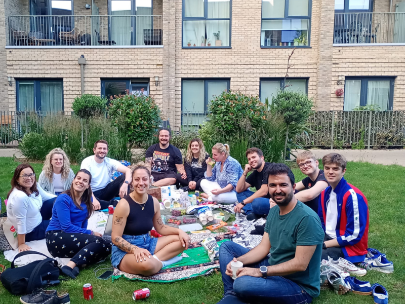 Residents picnic together on a green space by their homes. 