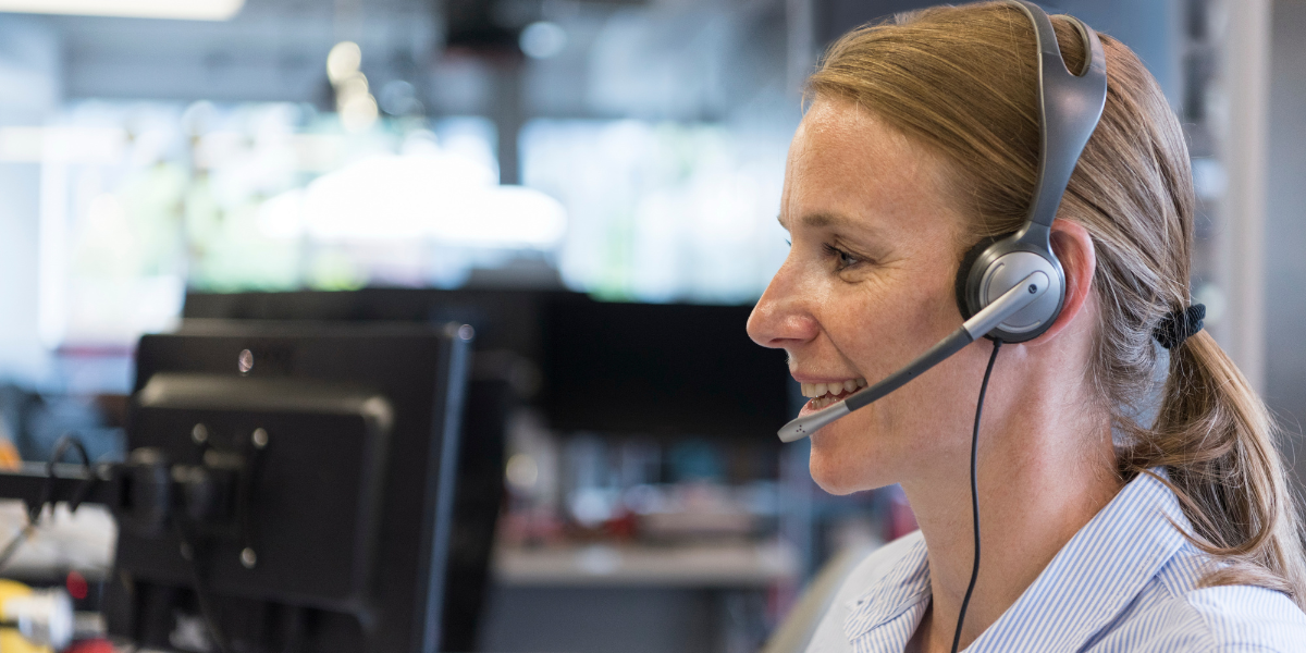 A woman answering a phone call while wearing a headset.