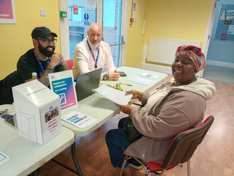 Staff speaking with a smiling resident at a Neighbourhood Night event.