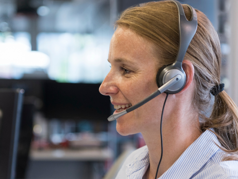 A woman wearing a headset takes a phone call. 