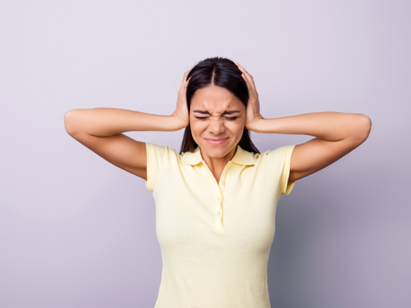 A woman covers her ears with her hands.