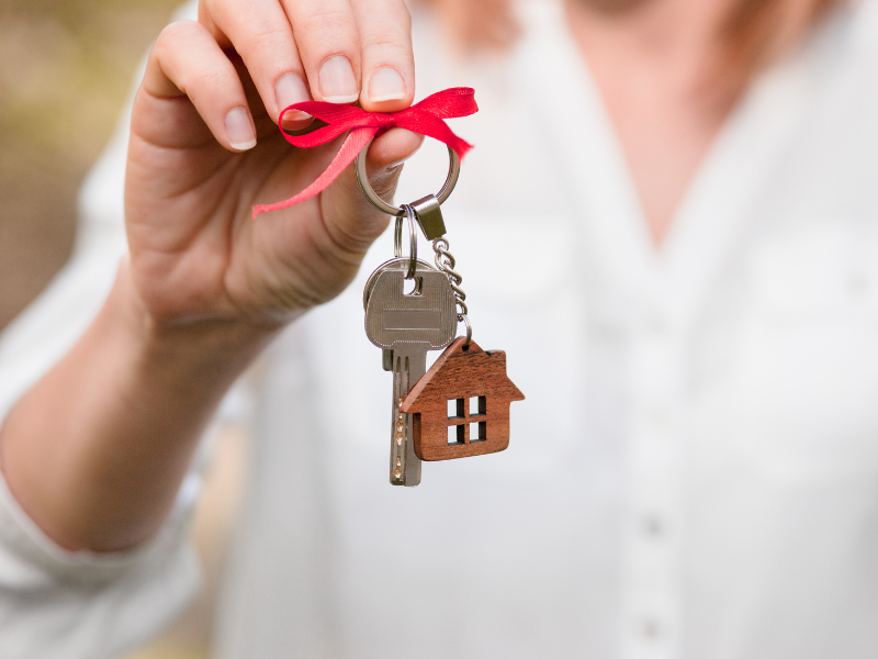 Set of keys with a house shaped keyring and a ribbon tied around it.